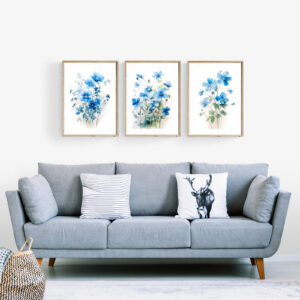 Cozy living room sofa in light blue with a 3-piece set of blue floral botanical wall art