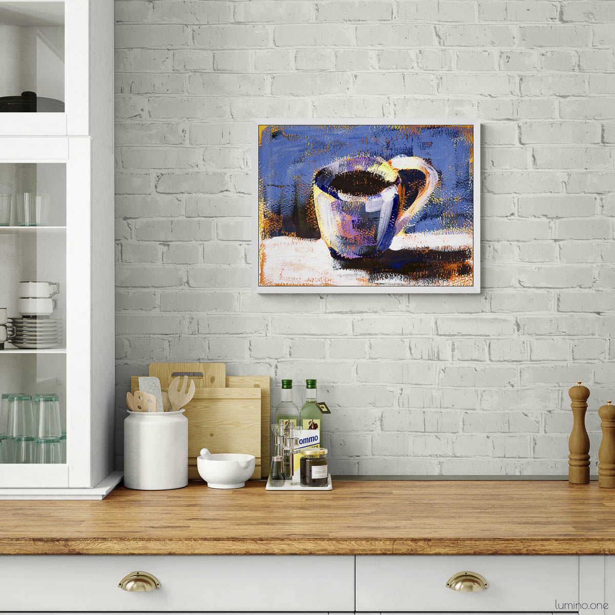 Blue abstract coffee mug painting displayed in white kitchen with brick wall, gold pendant lights, kitchen wall decor above wooden countertop, modern home art