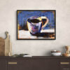 Coffee cup art print in black frame displayed on textured white wall above dark wood kitchen cabinet. Impressionist style coffee mug painting with vibrant blue background, styled with wooden cutting boards, kitchen utensils, stacked plates and wooden bowls. Modern kitchen wall decor for coffee lovers, perfect for coffee bar, breakfast nook, or dining area with natural wood accents.