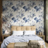 Classic blue peony toile wallpaper displayed as bedroom accent wall with tufted headboard, blue linens and contemporary bedroom decor
