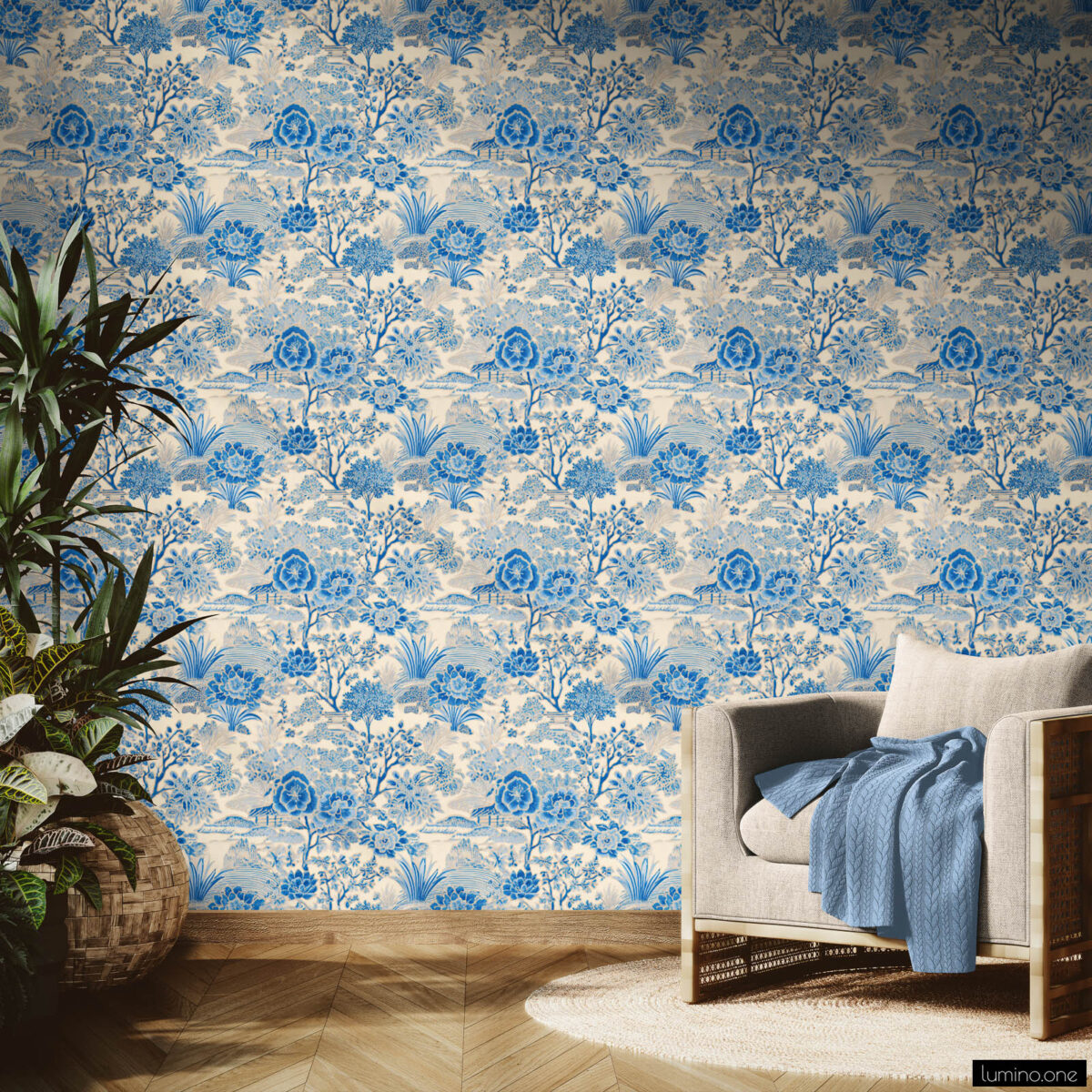 Blue Toile Peel and Stick Wallpaper - French Country Botanical P Blue and white toile peel and stick wallpaper on a full accent wall in a bright modern living room, featuring a vintage botanical garden pattern with flowers and trees. Styled with a linen armchair with blue throw blanket, large tropical houseplants in wicker baskets, herringbone wood floors, and floor-to-ceiling windows.