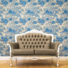 Blue and White Toile Peel and Stick Wallpaper - Vintage Botanica Blue and white toile peel and stick wallpaper covering a full wall behind an ornate French-style tufted leather loveseat with silver carved wood frame, featuring a vintage botanical garden pattern with large peony flowers and trees. Styled on a warm honey herringbone wood floor, showcasing a classic French country living room aesthetic.