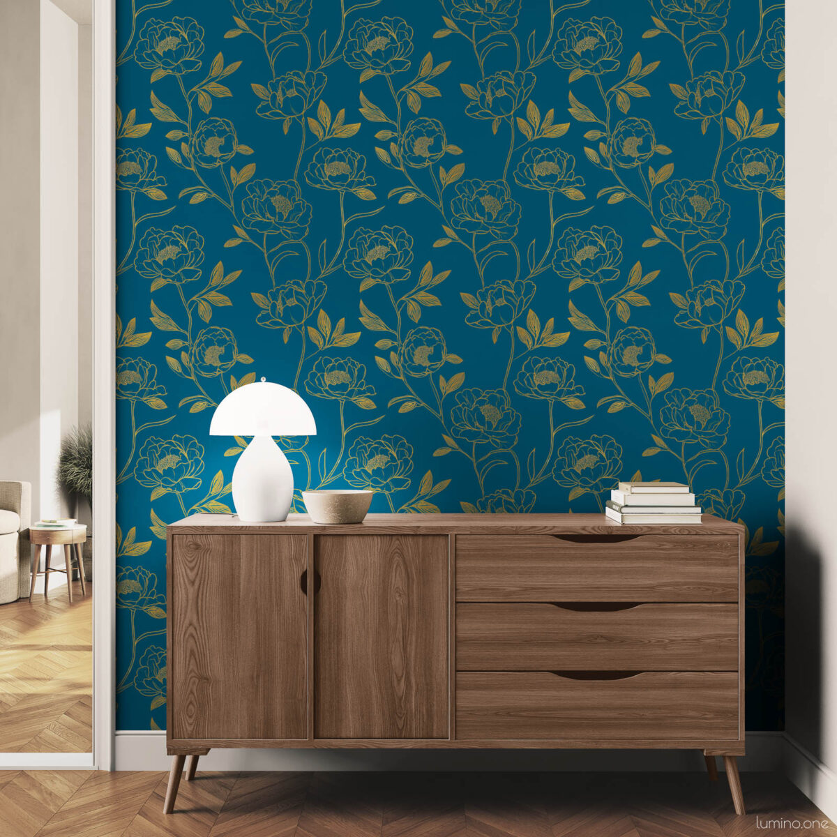Modern hallway accent wall with dark teal and gold botanical peony peel and stick wallpaper, styled with a mid-century walnut dresser, white mushroom table lamp, and stacked books on a herringbone wood floor